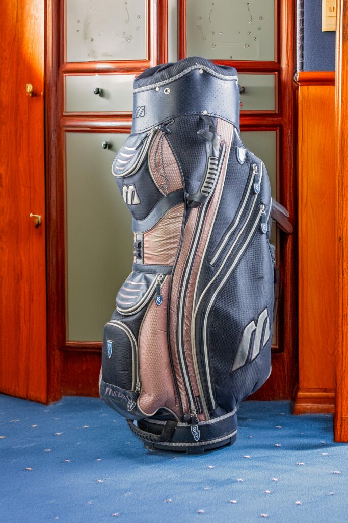 Detailed image of a premium golf bag against a classic wooden backdrop.